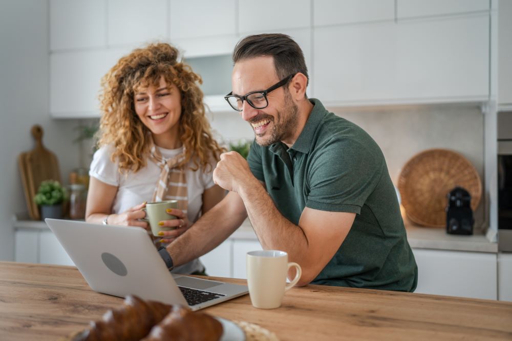 Couple using laptop at their kitchen