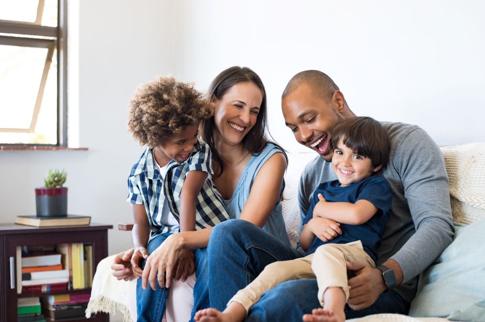 Diverse couple with children sitting on a couch smiling